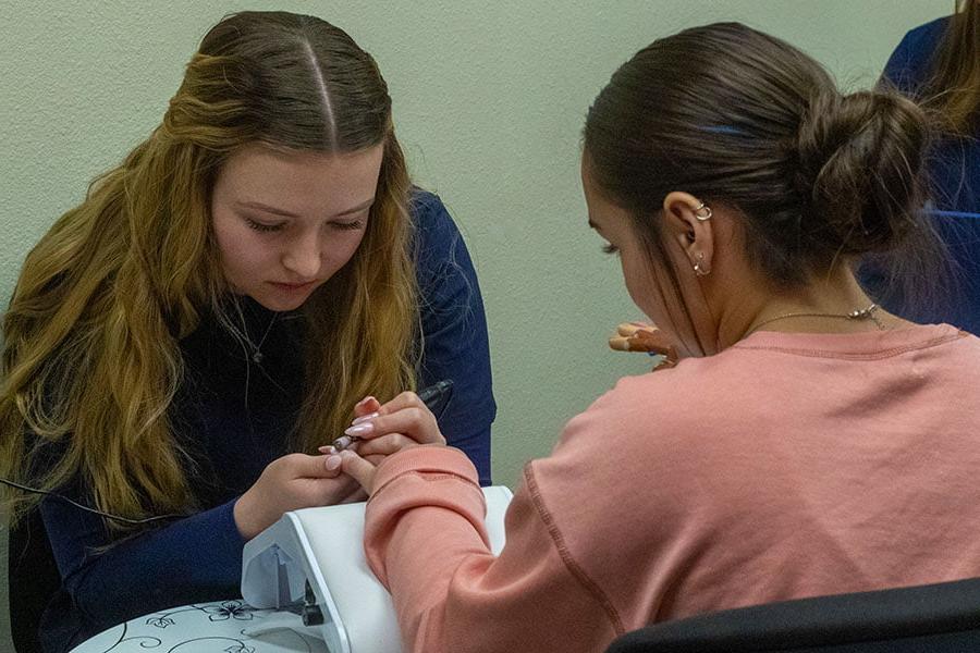 A San Juan College student giving a manicure